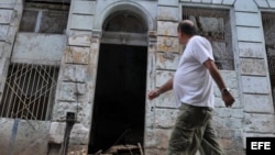 Un hombre camina frente a un edificio que se derrumbó parcialmente debido a las fuertes lluvias y que se encuentra ubicado en el barrio de Centro Habana, en La Habana (Cuba).