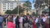 Un grupo de personas se reúne a cielo abierto frente a un supermercado Publix después de abandonar los edificios circundantes en el área del centro comercial Dadeland.