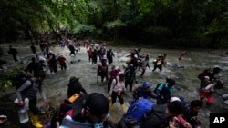 Migrantes, en su mayoría venezolanos, cruzan un río durante su viaje a través del Tapón del Darién desde Colombia hacia Panamá, con la esperanza de llegar a Estados Unidos, (AP Foto/Fernando Vergara, Archivo)